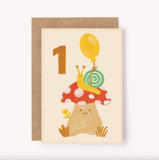 This cute first birthday card is the perfect way to mark a birthday milestone!  Featuring an illustrated snail with a bright balloon tied to its shell, perched on top of a sweet spotty mushroom A bold hand-lettered number 1 sits on a soft beige background - the colour palette makes it a gender neutral greeting card, ideal for celebrating any child turning one.