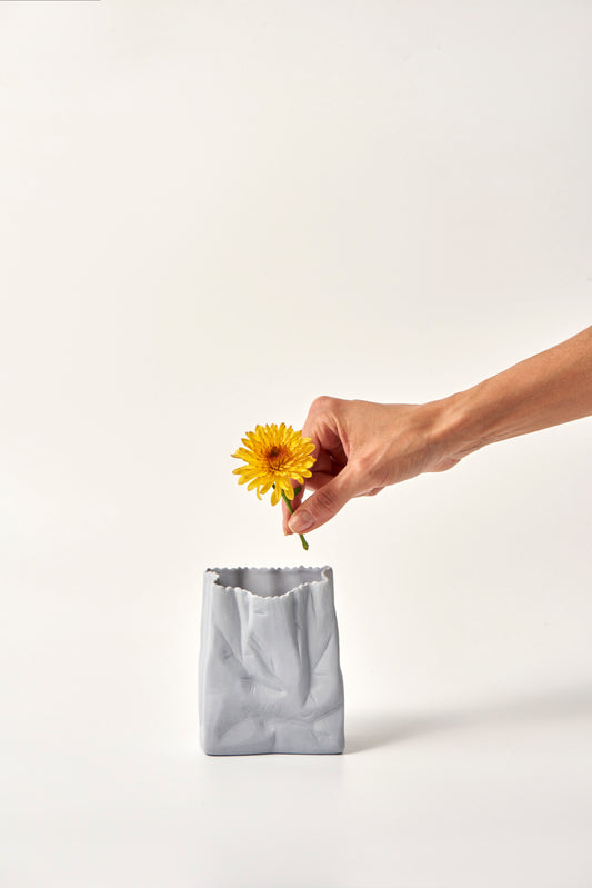 This humble yet iconic piece has been a part of our collection since 2006, and this season, it's back with a fresh twist. Crafted from delicate bone china, it captures the familiar charm of a crumpled paper bag. Versatile and unique, it's perfect for displaying your favourite blooms, organizing pencils on your desk, holding toothbrushes in the bathroom, or even keeping cutlery neatly arranged.