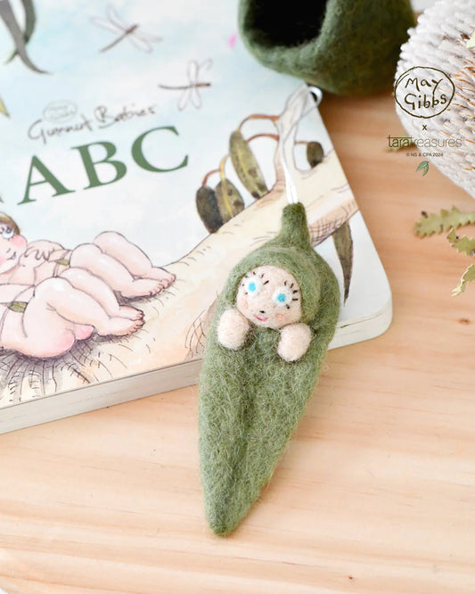 Inspired by the beloved Australian children's books, this felt Gumnut Baby ornament captures the whimsy and wonder of Snugglepot and Cuddlepie's adventures in the bush.  Dive into the enchanting world of May Gibbs™ with Tara Treasures®&nbsp; exquisite range of felt products, lovingly crafted under license from the timeless illustrations of this Australian icon. 