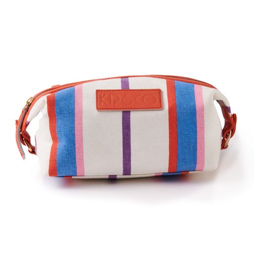 The Maldives Stripe Toiletry Bag features a blue, red, pink and purple stripe pattern on a white base with blue trim details and melon red leather branding.  100% cotton canvas.   22 x 14 x 11 cm.
